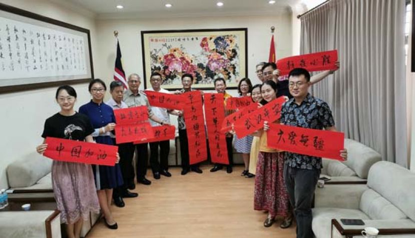 砂拉越地方政府与房屋部长兼砂人联党主席拿督斯里沈桂贤（右七）与中国驻古晋总领事程广中（左六）携手展示&ldquo;天下华人同去病、中马两国共驱疾&rdquo;的对联，象征着中马两国携手共驱病毒。