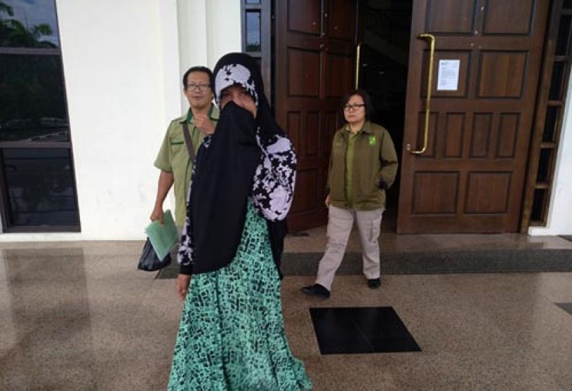 售卖龟鸡而被判处坐牢3个月的印尼妇女被森林局执法人员离开法庭时摄。