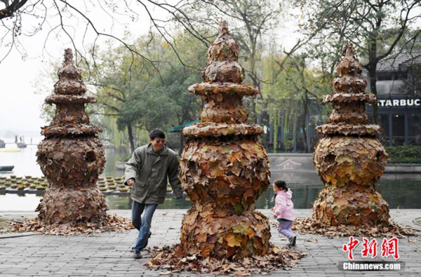 图示：一位市民和小朋友在落叶装饰成的&ldquo;三潭印月&rdquo;前嬉戏。