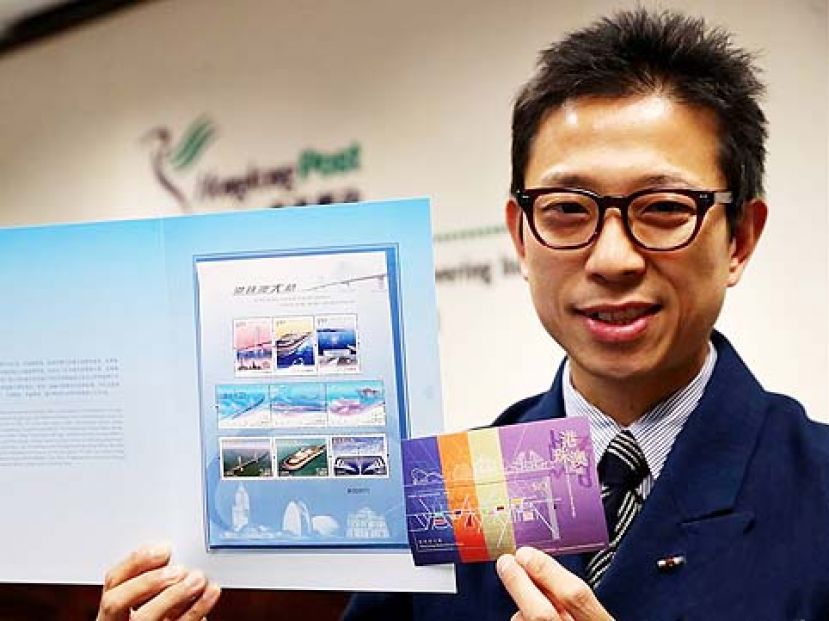 图示：香港邮政总局一名工作人员展示&ldquo;港珠澳大桥&rdquo;联合纪念套折和邮票小型张。