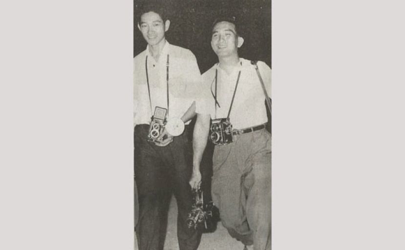 20世纪50年代末，当时未满20岁的梁国信（左）背着相机，正前往总督府采访时摄，走在他身边的是知名摄影师何亚传。