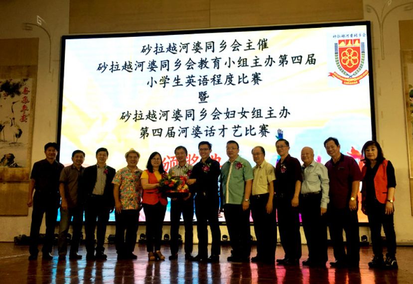  筹委会主席邓群娇（左5）在砂拉越河婆同乡会会长张添堡（左6）、名誉会长蔡文铎（右6）等人见证下赠送纪念品予砂行动党主席张健仁特别助理沈杰龙，右1为妇女组主任邓春梅。