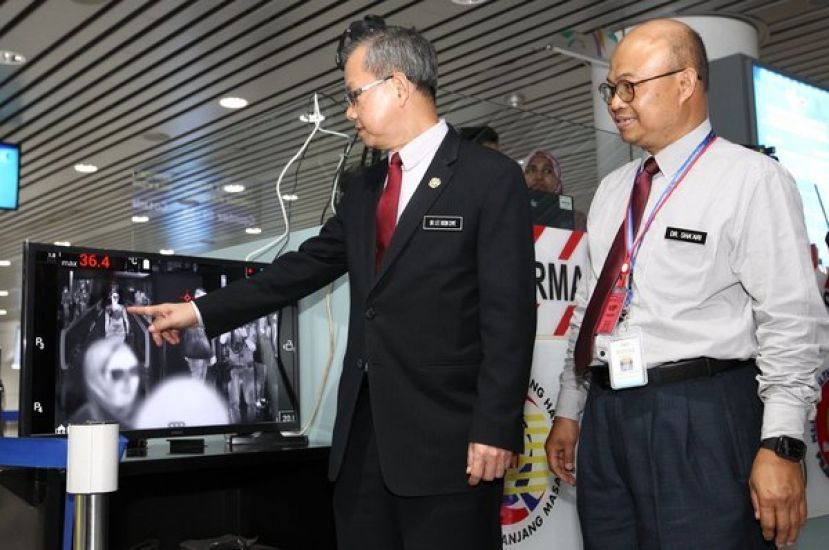 卫生部副部长李文材（左）与卫生官员在机场检视体温检测器的运作。