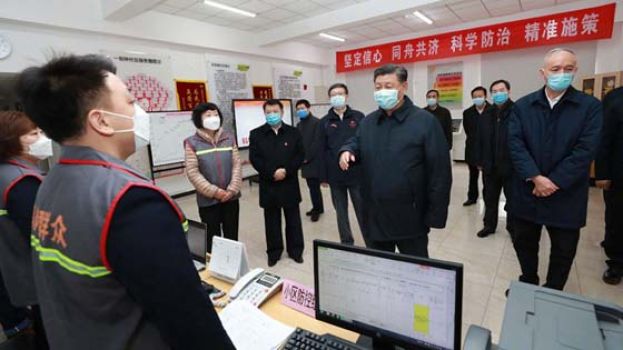 习近平听取工作人员介绍防疫情况。
