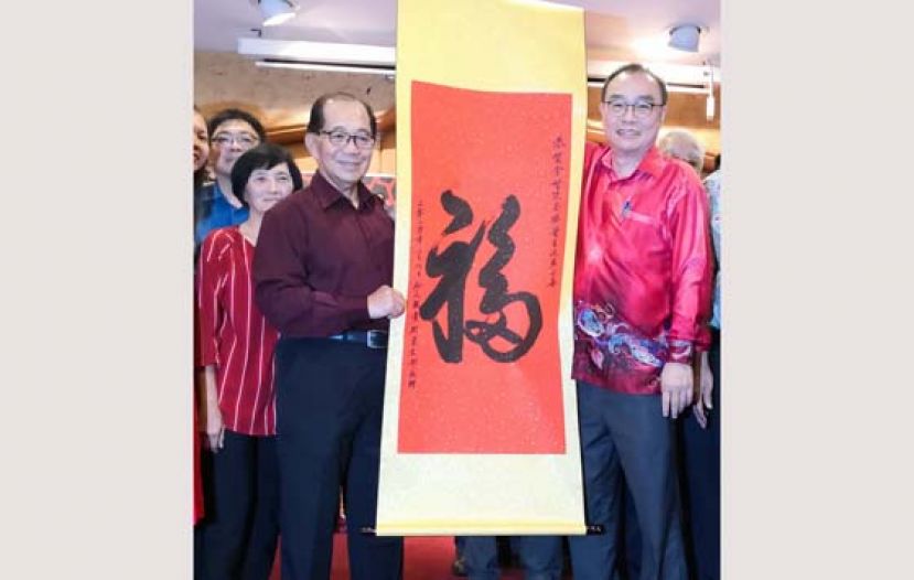 砂人联党都东支部主席黄振渊（右）赠送一幅&ldquo;福&rdquo;字画予拿督孙春德。